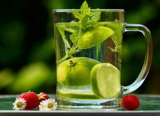 taza con agua, limón y hojas de menta
