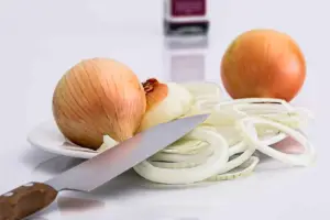 Cultivo de cebolla - Un plato con dos cebollas enteras y una rebanada