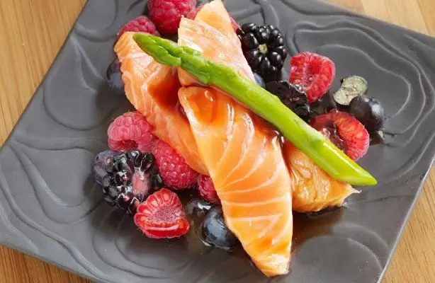 dos filetes de salmón emplatados con aderezo de frutas