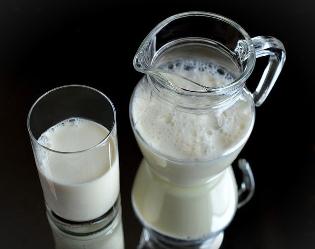 Vaso y jarra de cristal con leche para ser usada en la elaboración de mantequilla