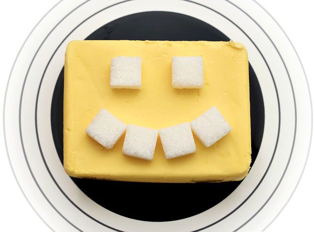 Una panela de mantequilla con unos cubos de azúcar en forma de cara feliz