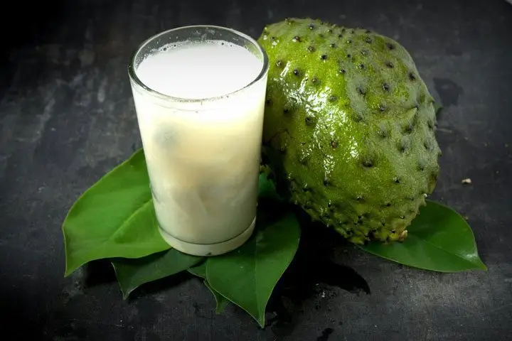 Una guanábana y un vaso con jugo de guanábana
