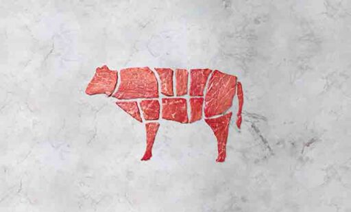 Cortes de carne org&aacute;nica de res fresca dispuestos en forma de silueta de vaca sobre un fondo de m&aacute;rmol gris.